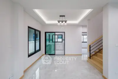 Modern open-plan living space with sleek staircase and large windows