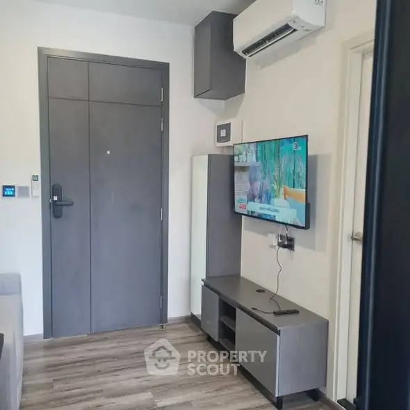 Modern living room with sleek furniture and wall-mounted TV, featuring air conditioning and stylish flooring.