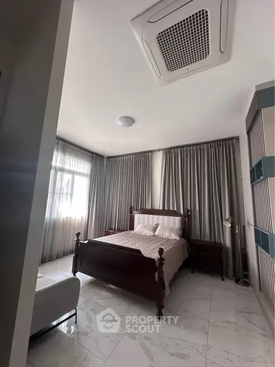 Spacious bedroom with elegant wooden bed and large windows for natural light.