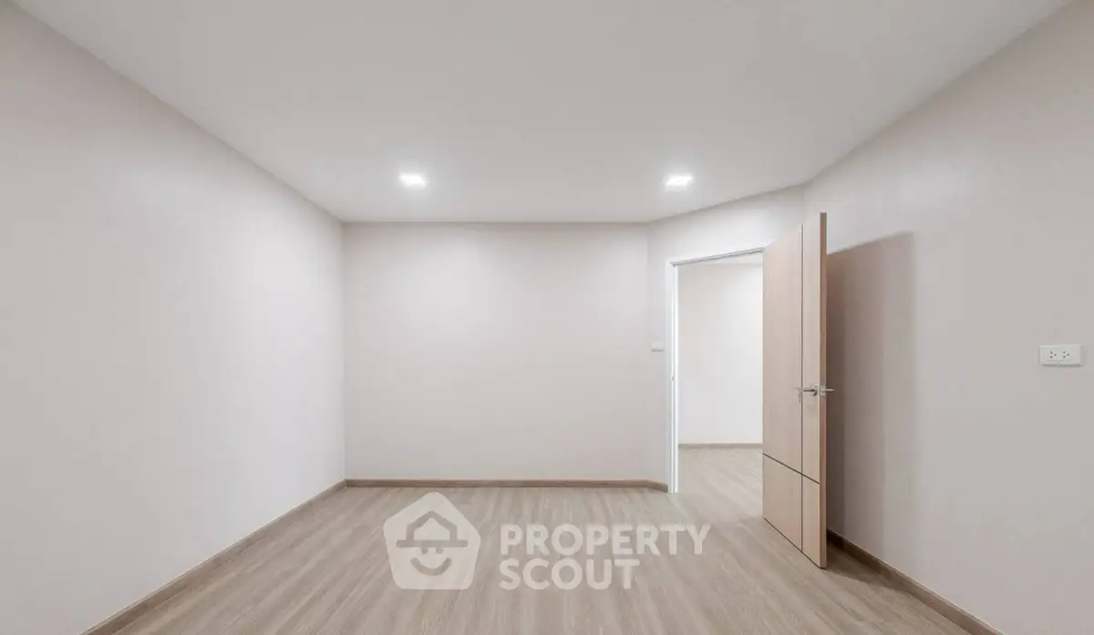 Spacious empty room with wooden flooring and open door, ideal for customization.