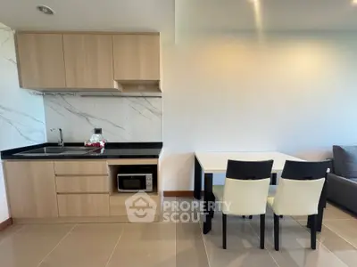 Modern kitchen with sleek cabinetry and dining area in open layout apartment.