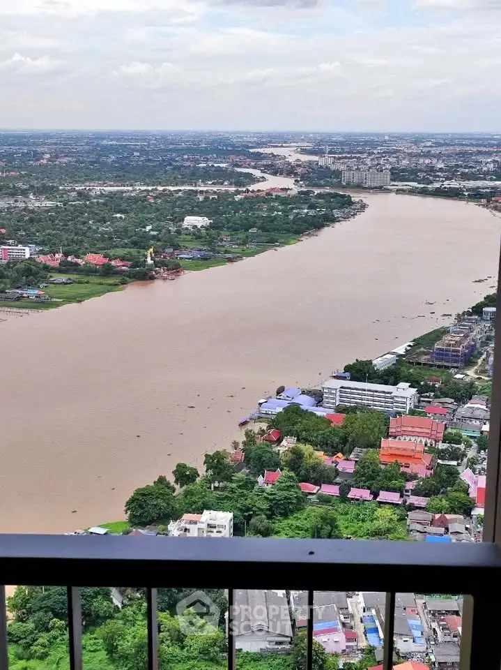 Stunning river view from high-rise balcony overlooking cityscape and lush greenery.