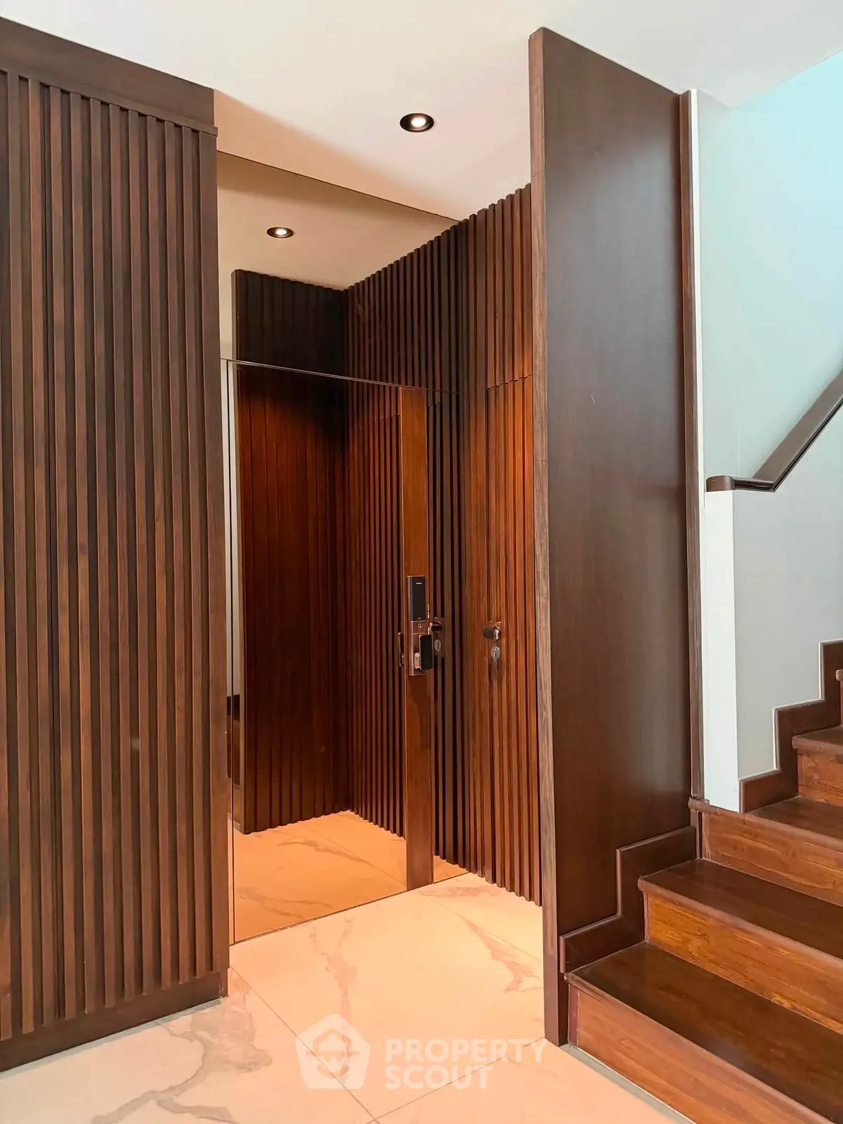 Elegant modern elevator entrance with wooden paneling and marble flooring in luxury building.