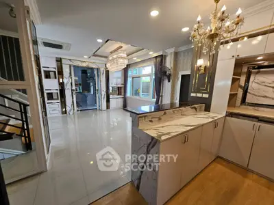 Luxurious open-plan kitchen with marble countertops and elegant chandeliers