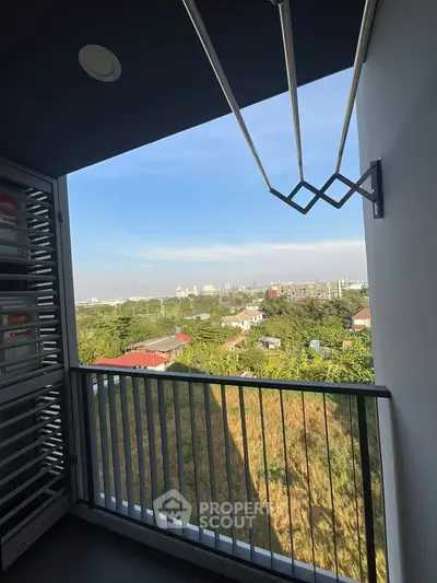 Scenic balcony view overlooking lush greenery and distant cityscape.