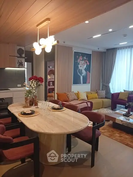 Stylish modern living room with elegant dining area and cozy seating, featuring chic decor and warm lighting.