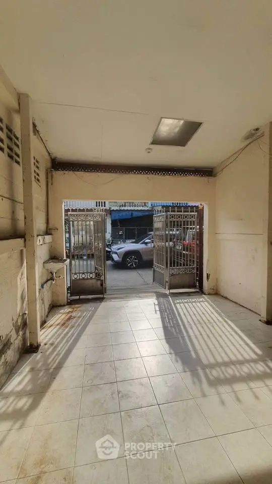 Spacious garage with open gate and tiled flooring, perfect for parking or storage.