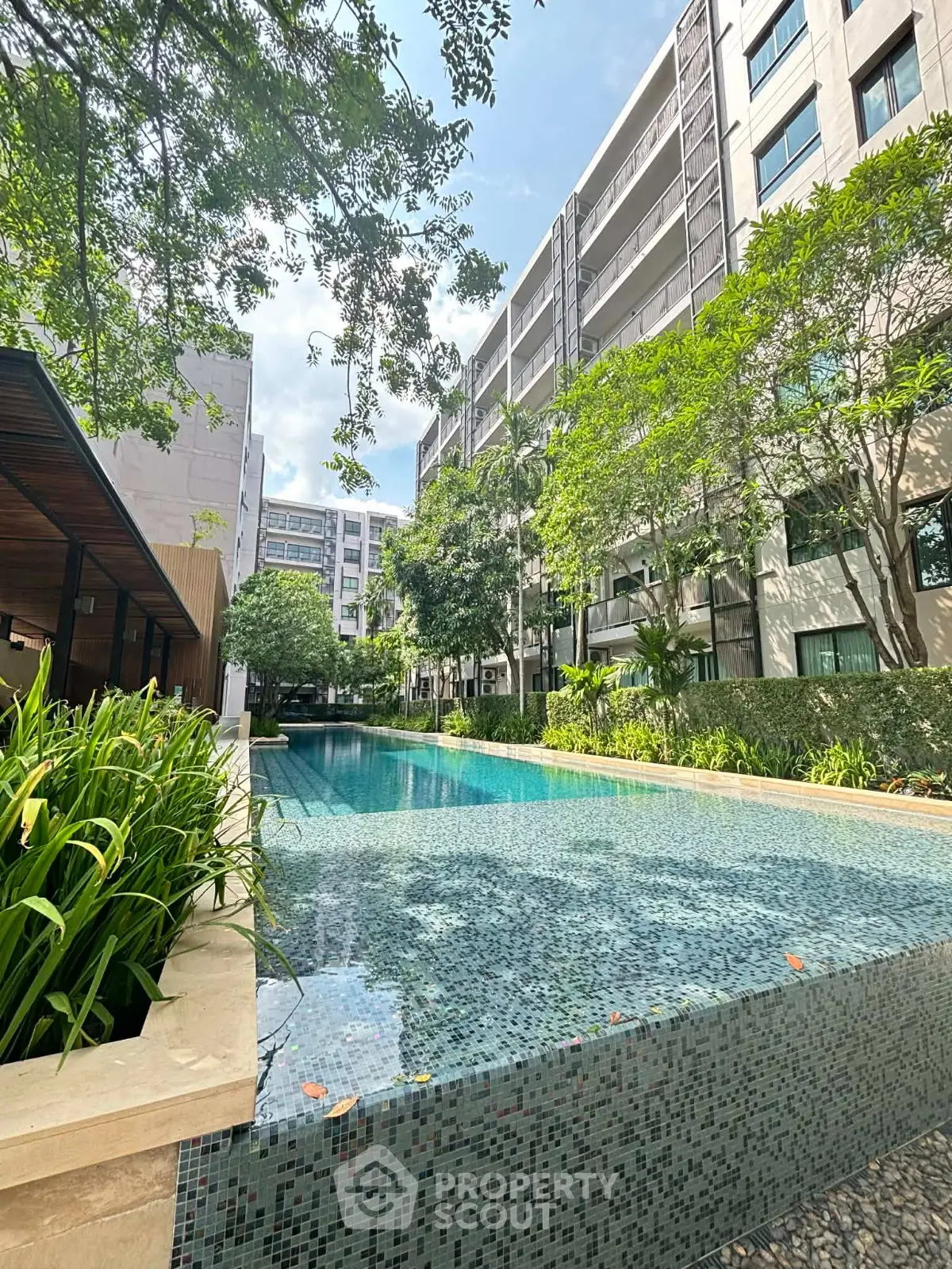 Luxurious apartment complex with stunning outdoor pool and lush greenery.