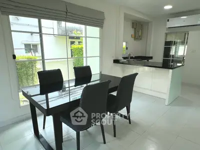 Modern dining area with sleek black table and chairs, adjacent to a stylish open kitchen.