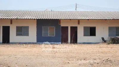 Single-story building with multiple units and a corrugated roof in a dry landscape.