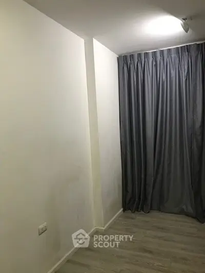 Minimalist room with gray curtains and light wood flooring