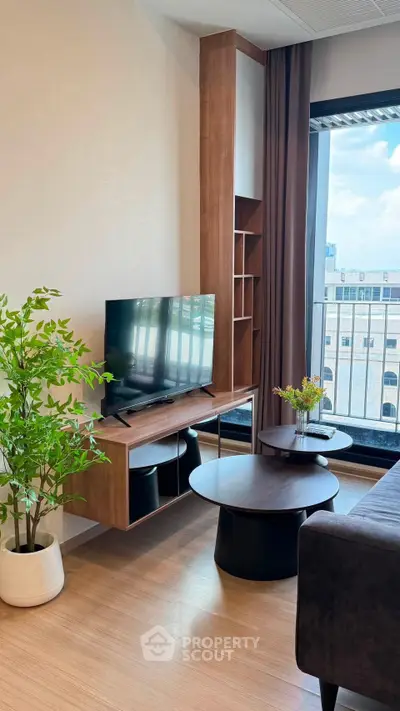 Modern living room with sleek furniture and large window offering city views.