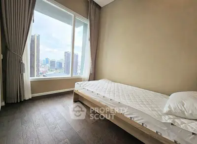 Modern bedroom with large window and city view, featuring minimalist decor and wooden flooring.