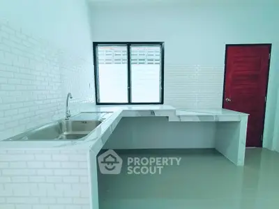 Modern kitchen with sleek countertops and stainless steel sink in a bright, minimalist design.