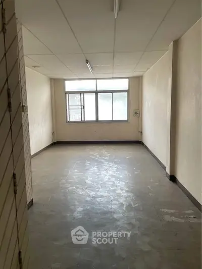 Spacious empty room with large window and tiled floor, ideal for customization.