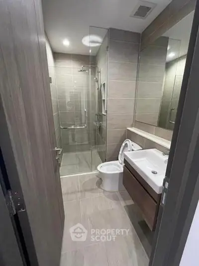 Modern bathroom with glass shower and sleek fixtures in a contemporary apartment.
