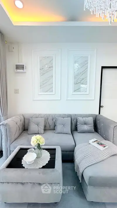 Elegant living room with plush gray sofa, chic decor, and modern lighting, perfect for stylish urban living.