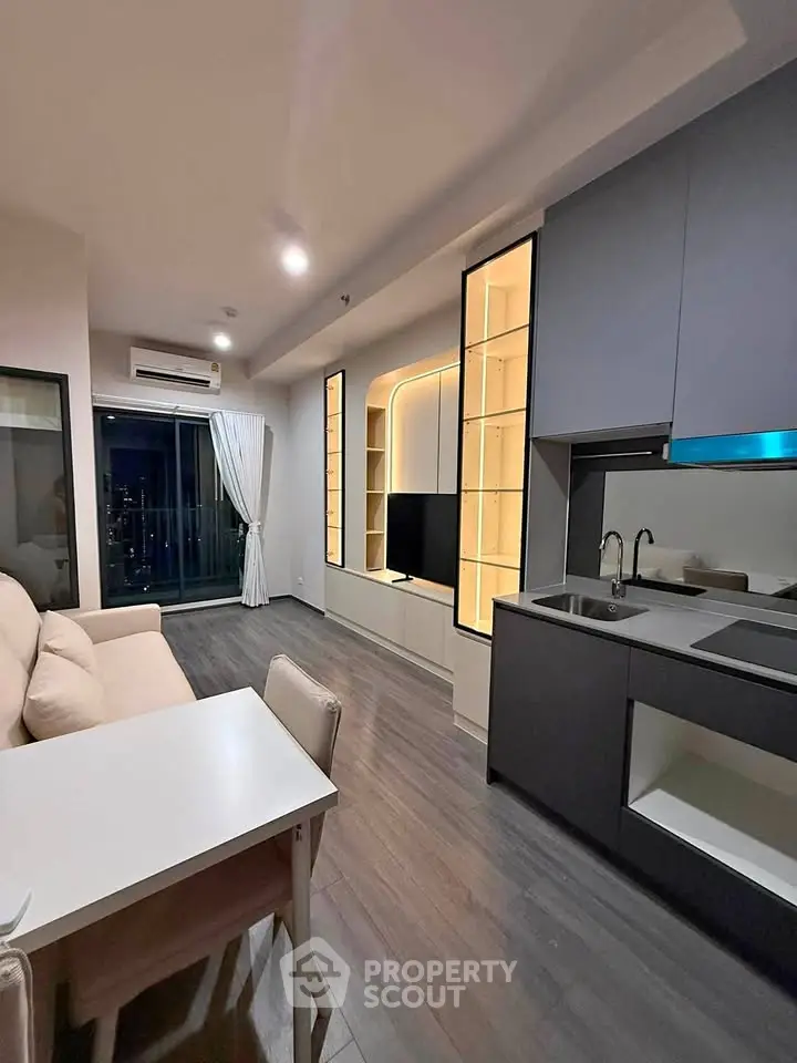 Modern open-layout living room with sleek kitchen and city view balcony.