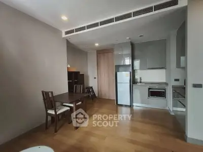 Modern apartment interior with open kitchen and dining area, featuring sleek appliances and wooden flooring.