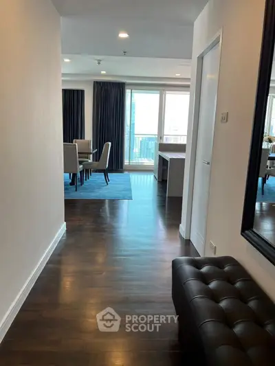 Spacious modern apartment hallway leading to elegant dining area with city view.