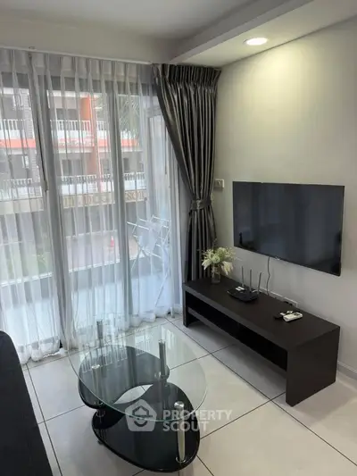 Modern living room with sleek TV setup and glass coffee table, featuring floor-to-ceiling windows and elegant curtains.