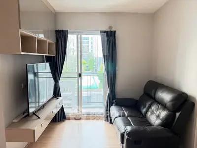 Modern living room with sleek furniture and large window offering a bright view of the outdoors.