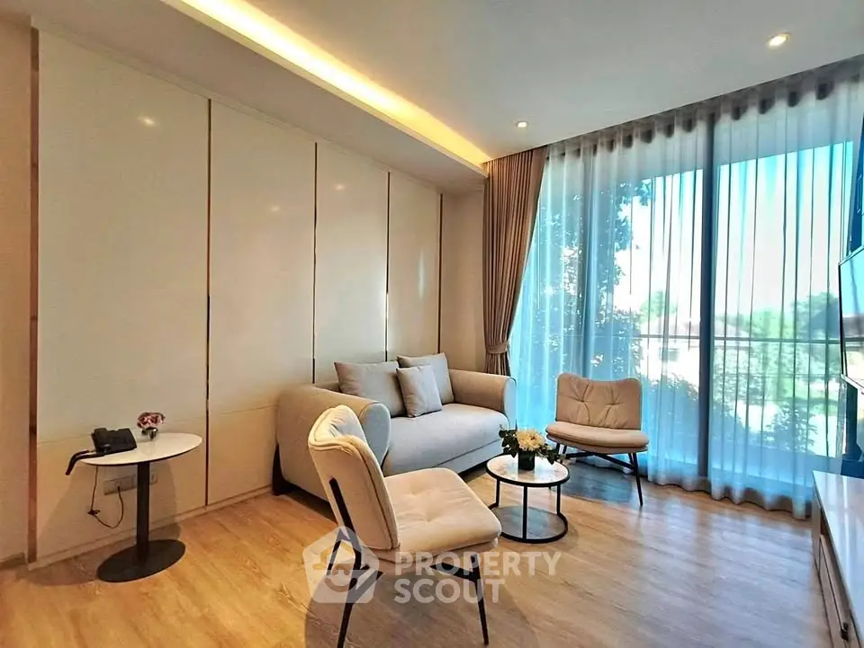 Modern living room with elegant furniture and large window offering natural light.