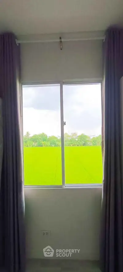 Stunning window view of lush green fields from a cozy interior space.