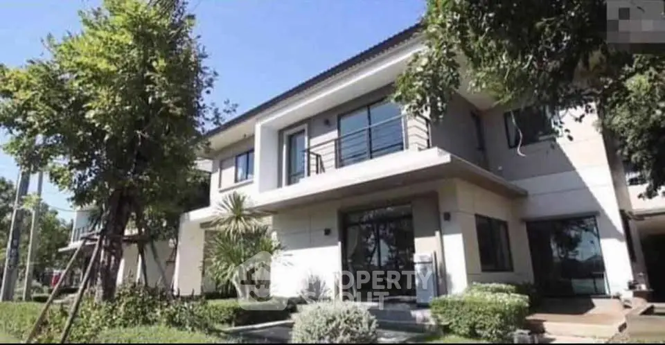 Stunning modern two-story house with lush garden and large windows.