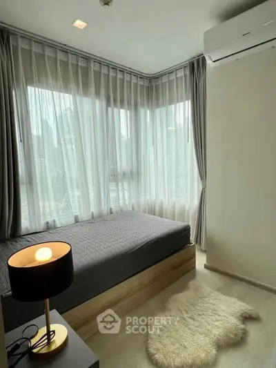 Cozy bedroom with city view, featuring modern decor and ample natural light.
