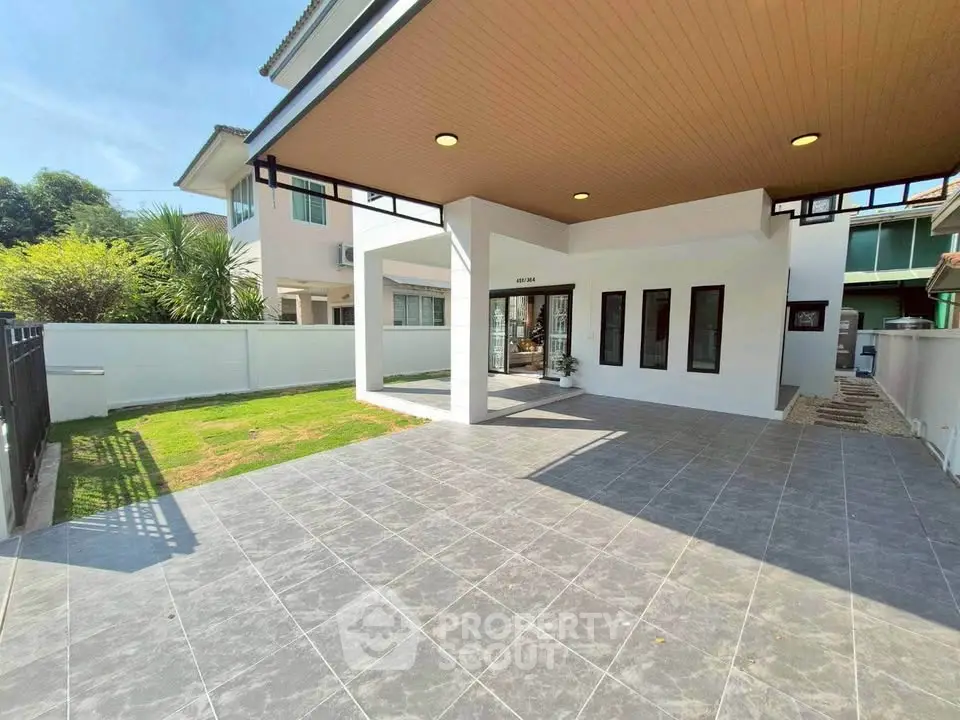 Spacious modern home exterior with tiled patio and lush green lawn, perfect for family gatherings.