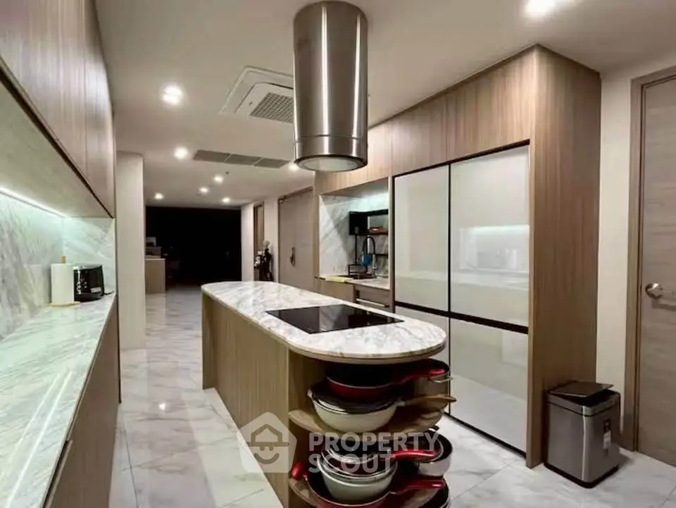 Luxurious modern kitchen with marble countertops and sleek wooden cabinetry, featuring an island and high-end appliances.