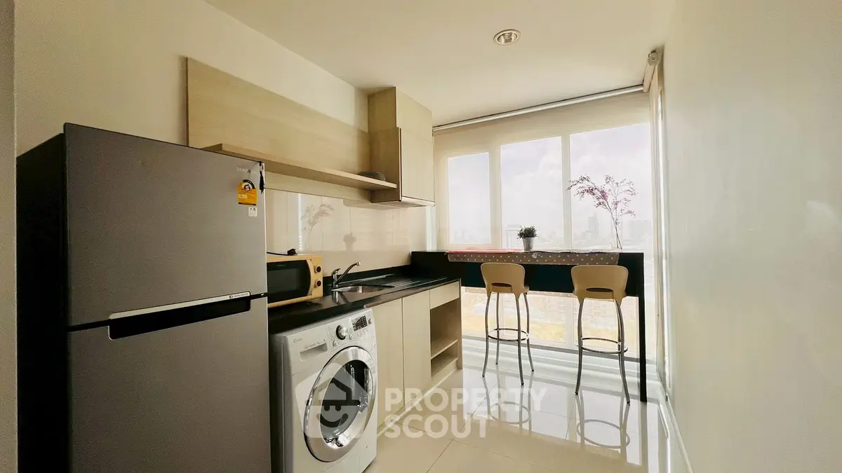 Modern kitchen with washing machine and breakfast bar with city view.