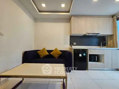 Modern living room with sleek kitchen, cozy sofa, and stylish lighting in a compact open layout.