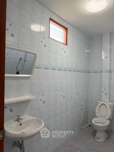 Spacious bathroom with modern fixtures and tiled walls, featuring a sink, mirror, and toilet.