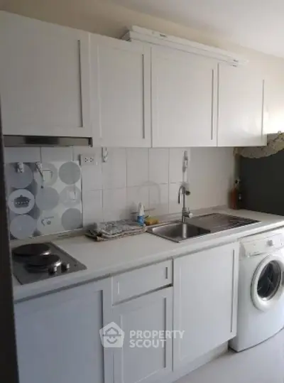 Compact kitchen with white cabinets and washing machine, ideal for modern living.