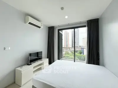 Modern bedroom with city view and balcony access in high-rise apartment.