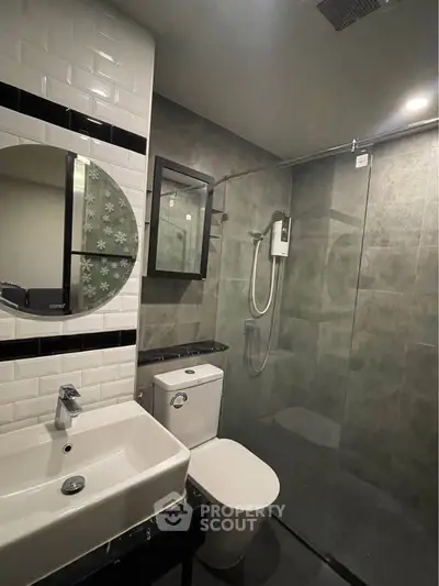 Modern bathroom with sleek design featuring a glass shower enclosure and stylish fixtures.