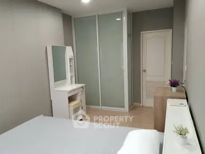 Modern bedroom with sleek wardrobe and vanity in neutral tones.