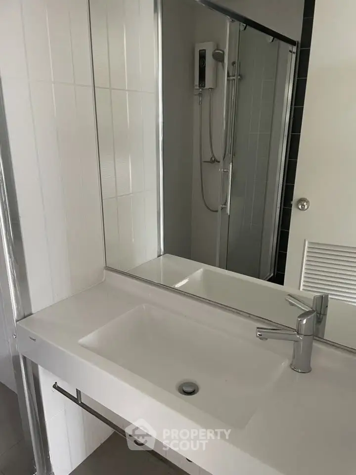 Modern bathroom with sleek sink and shower area in contemporary apartment.