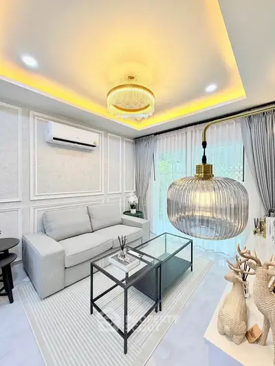 Elegant living room with modern chandelier and cozy sofa, featuring stylish decor and ambient lighting.