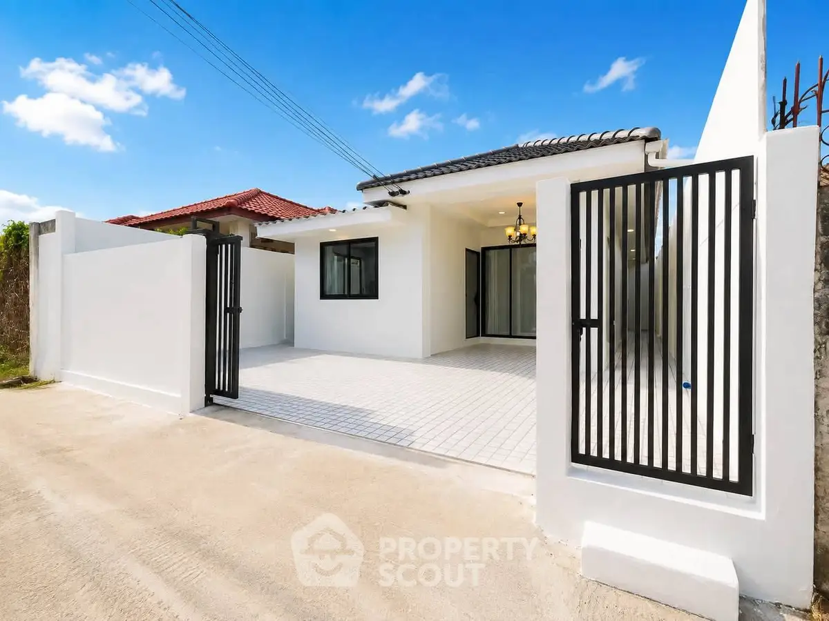 Charming modern house with gated entrance and spacious driveway under a clear blue sky.