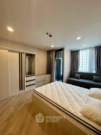 Spacious modern bedroom with large windows and elegant furnishings in a high-rise apartment.