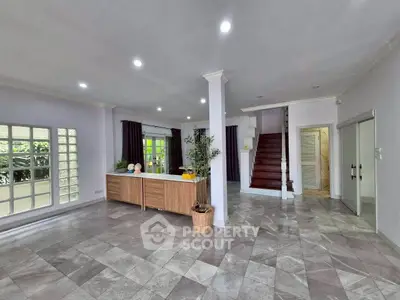 Spacious open-plan living area with modern tile flooring and elegant staircase.