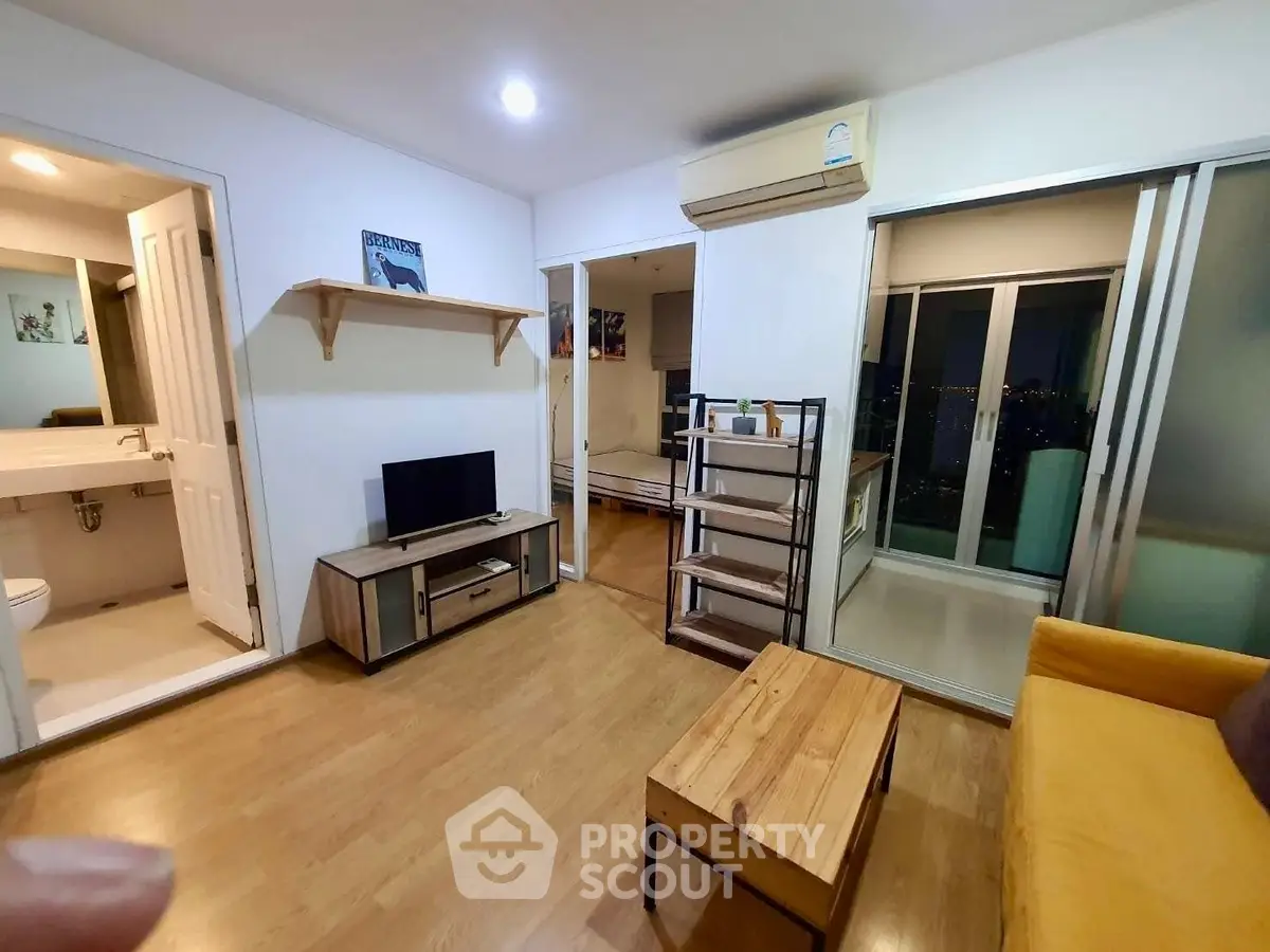 Modern living room with wooden flooring, cozy furniture, and balcony access in a stylish apartment.
