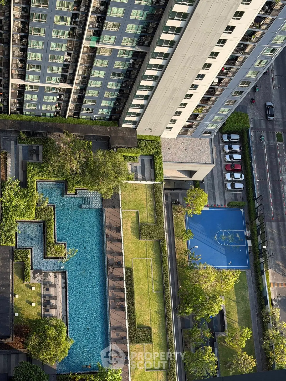 Stunning aerial view of modern apartment complex with pool and sports court, perfect for urban living.