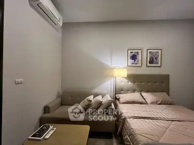Cozy bedroom with modern decor, featuring a comfortable bed, stylish sofa, and elegant wall art.