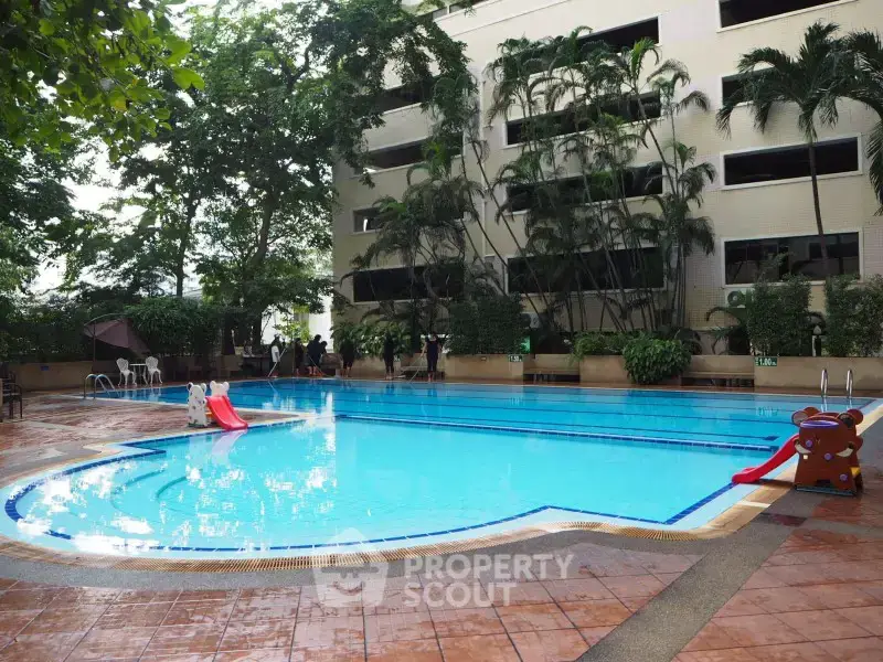 Luxurious residential building with inviting outdoor pool and lush greenery, perfect for relaxation and leisure.