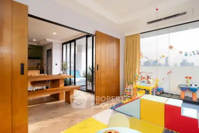 Spacious family-friendly living room with play area and city view balcony.