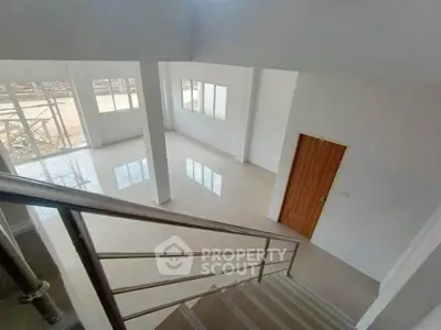 Spacious modern interior with large windows and sleek staircase, perfect for natural light lovers.